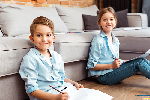 selective focus of happy siblings drawing in living room