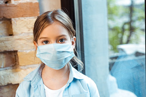 kid in medical mask  near window at home