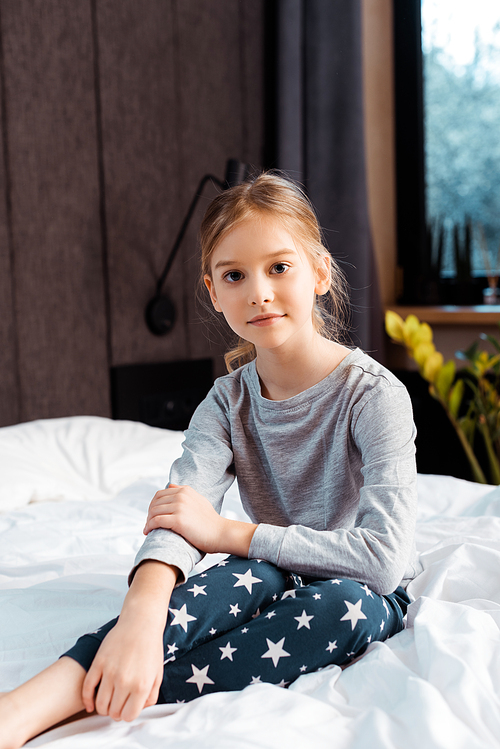 child  and smiling while sitting in bedroom