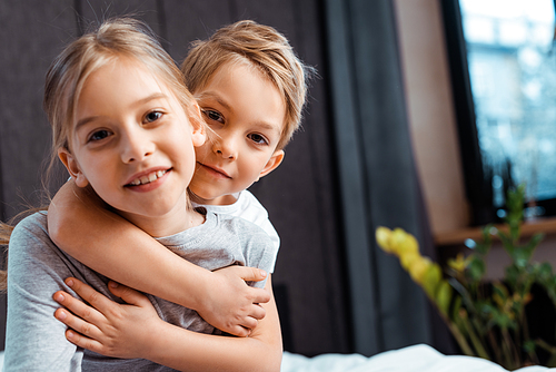 cute brother hugging happy sister at home