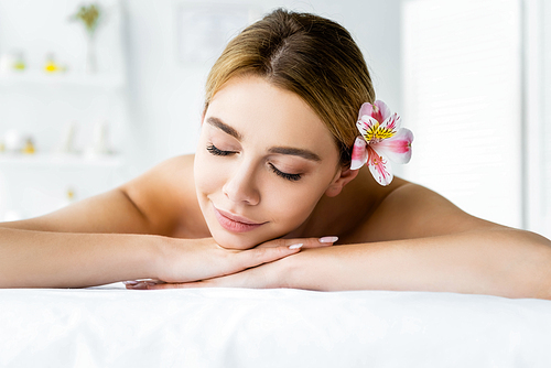 attractive woman with flower lying on massage mat in spa