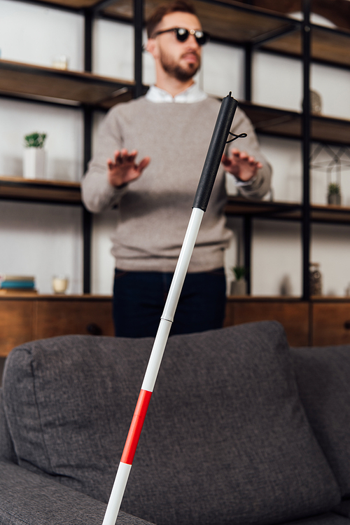 Selective focus of walking stick and blind man in living room