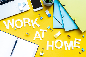 Top view of work at home lettering near open notebook and stationery on yellow background