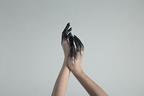Cropped view of witch hands in black paint isolated on grey