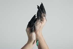 Cropped view of witch hands in black due holding crystal isolated on grey