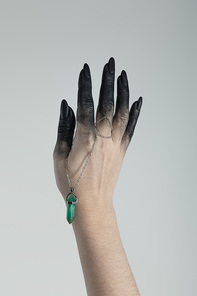 Cropped view of witch hand in black paint holding crystal isolated on grey