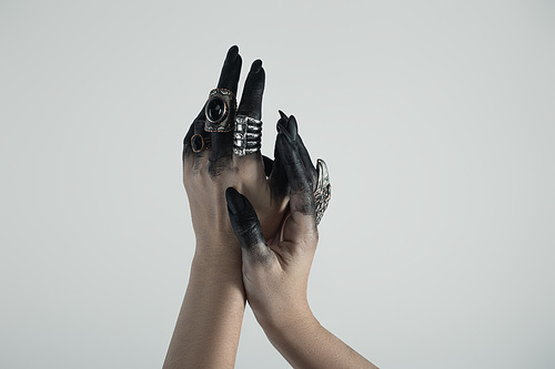 Cropped view of hand of witch in black paint with jewelry rings isolated on grey