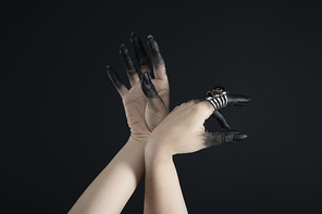 Cropped view of black painted fingers of witch hands with jewelry rings isolated on black