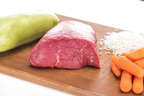 raw meat, food, carrot and zucchini on wooden cutting board isolated on white