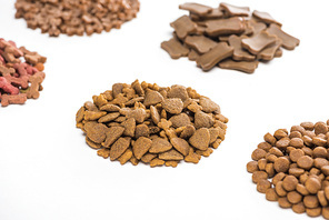 selective focus of fresh assorted dry pet food in piles isolated on white