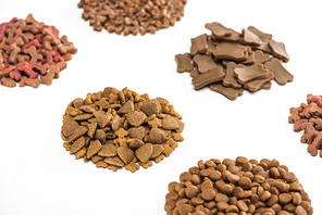 selective focus of fresh assorted dry pet food in piles isolated on white