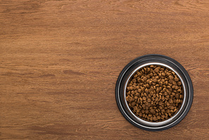 top view of dry pet food in silver bowl on wooden table