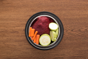 top view of raw vegetables and meat in bowl on wooden table