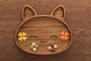 top view of feline dry pet food and vitamins in cute cat shape plate on wooden table