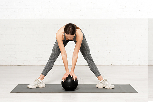 athletic woman in sportswear working out with black ball