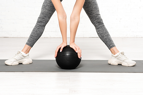 cropped view of young woman in sportswear working out with black ball