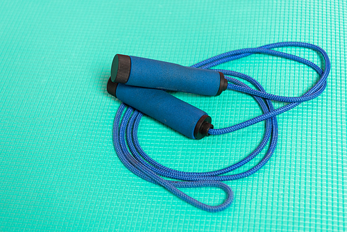 blue skipping rope on turquoise fitness mat