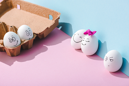 eggs with various face expressions on blue and pink with copy space