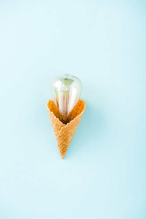top view of glass lightbulb in ice cream cone isolated on blue