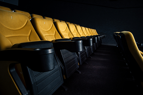 selective focus of orange seats with cup holders in cinema hall