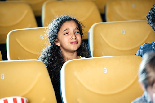 cute sad african american child crying while watching movie in cinema