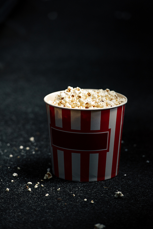 stripped red and white paper cup with popcorn on cinema hall floor