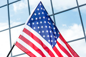low angle view of american flag near glass building with windows