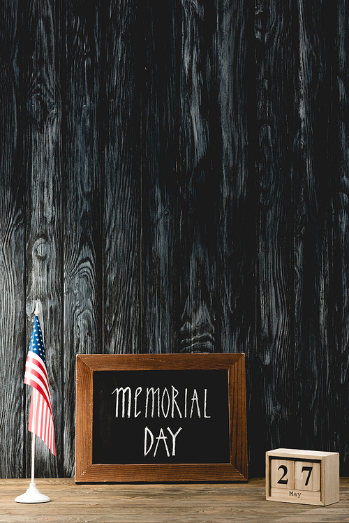 chalkboard with memorial day lettering near american flag and cubes with date
