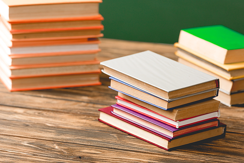 colorful hardcover books on wooden surface isolated on green