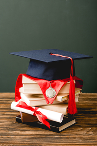 books, academic cap, medal and diploma on wooden surface isolated on grey
