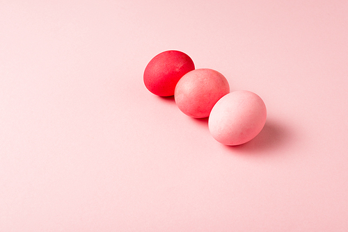 three colorful painted easter eggs on pink surface