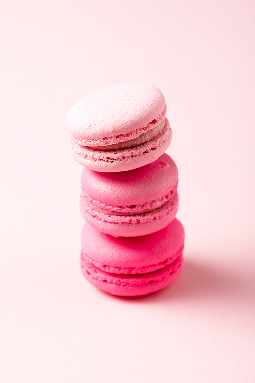 three colorful tasty macarons with filling on pink