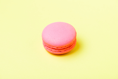 pink macaron cookie with filling on yellow surface