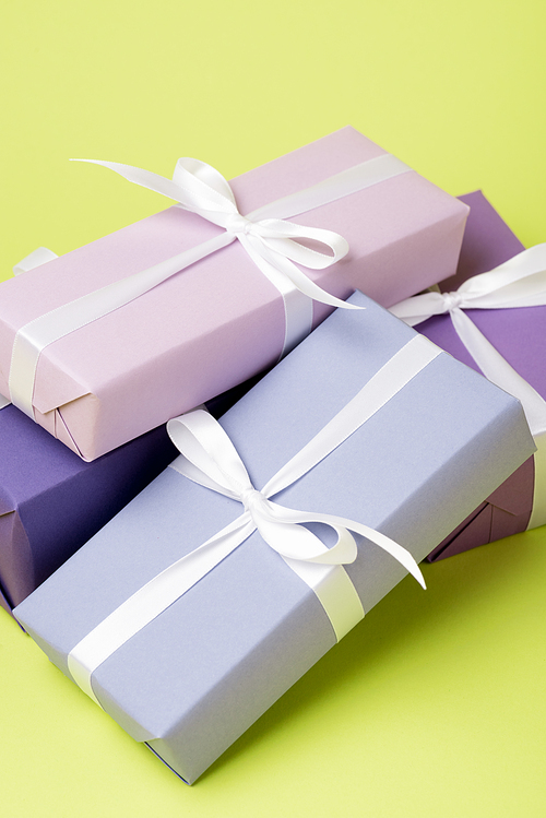 purple gift boxes with white ribbons on yellow surface