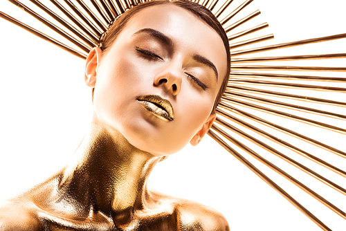 naked beautiful young woman painted in golden with accessory on head and closed eyes isolated on white