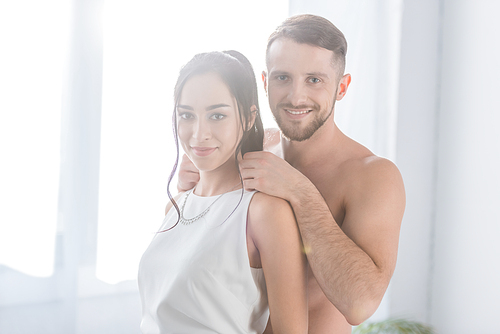 cheerful muscular man standing with happy brunette girlfriend