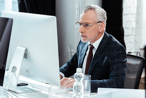 selective focus of businessman in glasses working in modern office