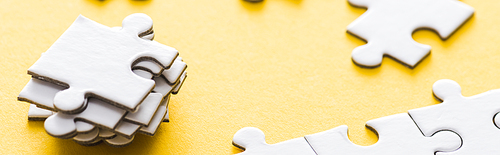 panoramic shot of stacked white puzzle pieces on yellow