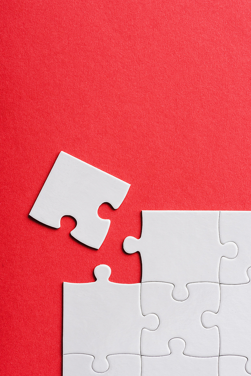 top view of unfinished white jigsaw puzzle pieces isolated on red