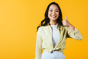 attractive asian girl showing thumb up isolated on yellow