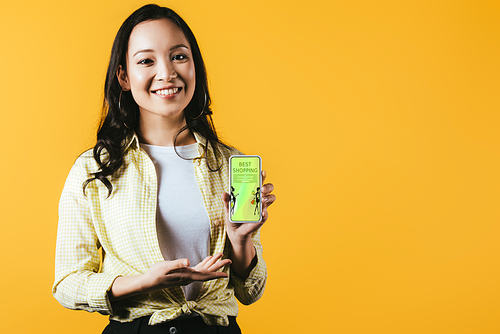 happy asian girl presenting smartphone with best shopping app, isolated on yellow