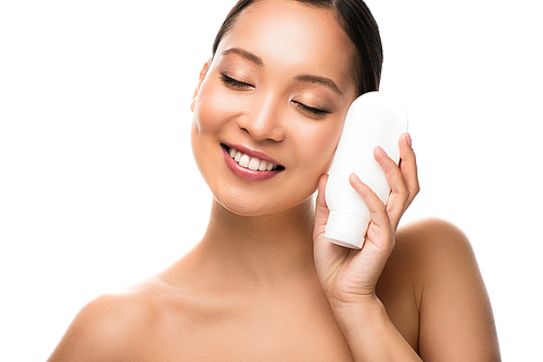 smiling asian woman with closed eyes holding bottle of lotion, isolated on white
