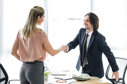 happy businessman shaking hands with client in office