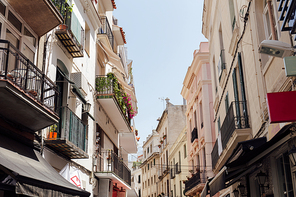 Urban street with sunlight on facade and plants on balcony in Catalonia, Spain