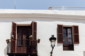 White facade of building with wooden shutters on window and balcony door in Catalonia, Spain