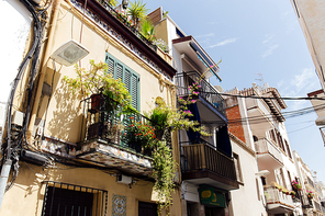 Urban street with plants on balcony and blue sky at background in Catalonia, Spain