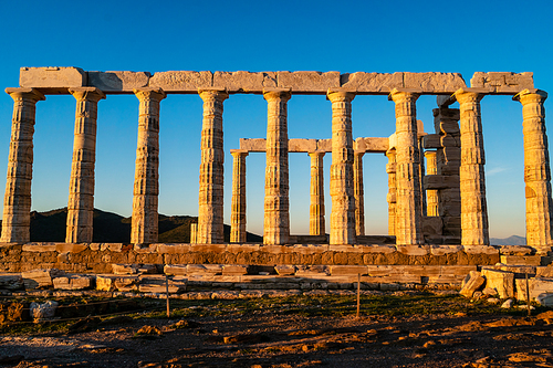 sunshine on ancient columns of parthenon in athens against blue sky