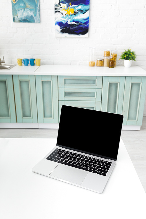 selective focus of laptop with kitchenware and abstract paintings on background