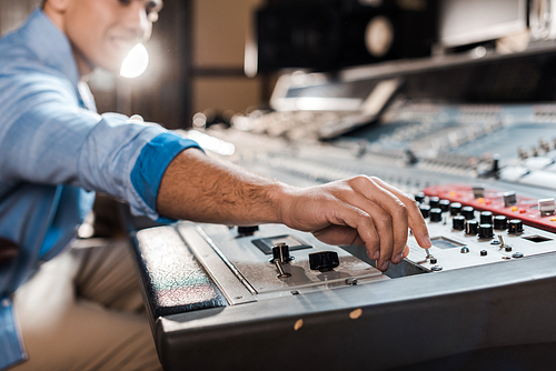 selective focus of mixed race sound producer working at mixing console