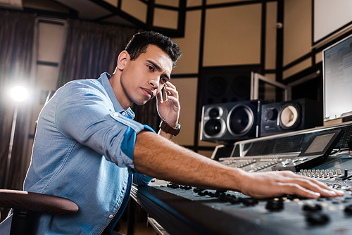 handsome, attentive mixed race sound producer working at mixing console